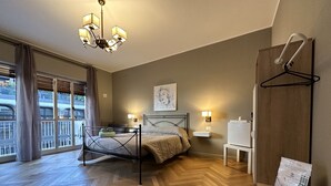 Ein Schlafzimmer mit Bett, Nachttischlampen, Holzboden, Blick ins Freie und einem Kleiderhaken.