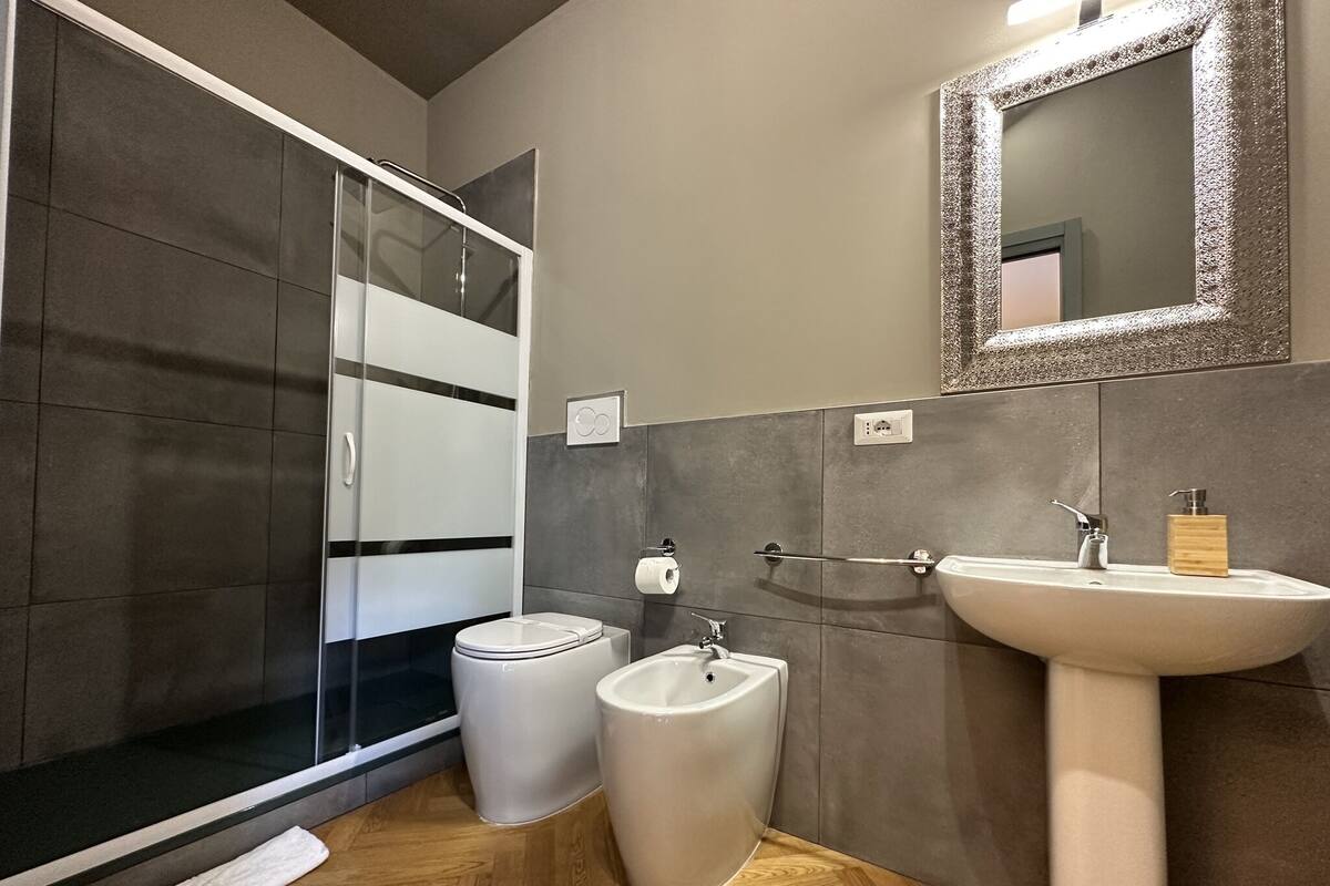 A modern bathroom with a shower, toilet, and sink.