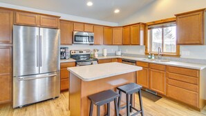 A modern kitchen with wooden cabinets, stainless steel appliances, and a central island with stools. - Cozy Belgrade Home Near Skiing, Hiking & Airport! (Belgrade)