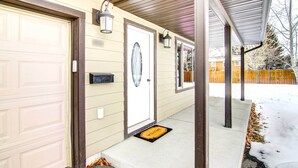 A residential house with a garage door, a front door with a doormat, and a covered porch area. - Cozy Belgrade Home Near Skiing, Hiking & Airport! (Belgrade)