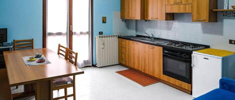 Una cocina compacta con gabinetes de madera, estufa y refrigerador.