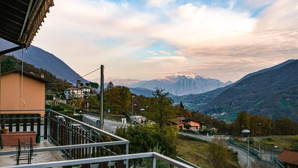 A balcony with a view of a mountain range and a town below. - Inviting 1-bed Apartment With Box and Seeviews (Ranzanico)