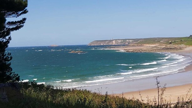 Paisaje costero con playa, océano y acantilados.