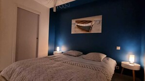 Un dormitorio con cama, dos lámparas de noche, una puerta y una obra de arte colgada en la pared.