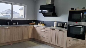Una cocina moderna con armarios de madera, un lavabo de acero inoxidable, un microondas y un horno.
