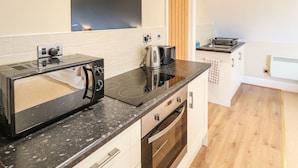 A modern kitchen with a built-in microwave, toaster, and electric kettle. - Granary Loft (Grantham)