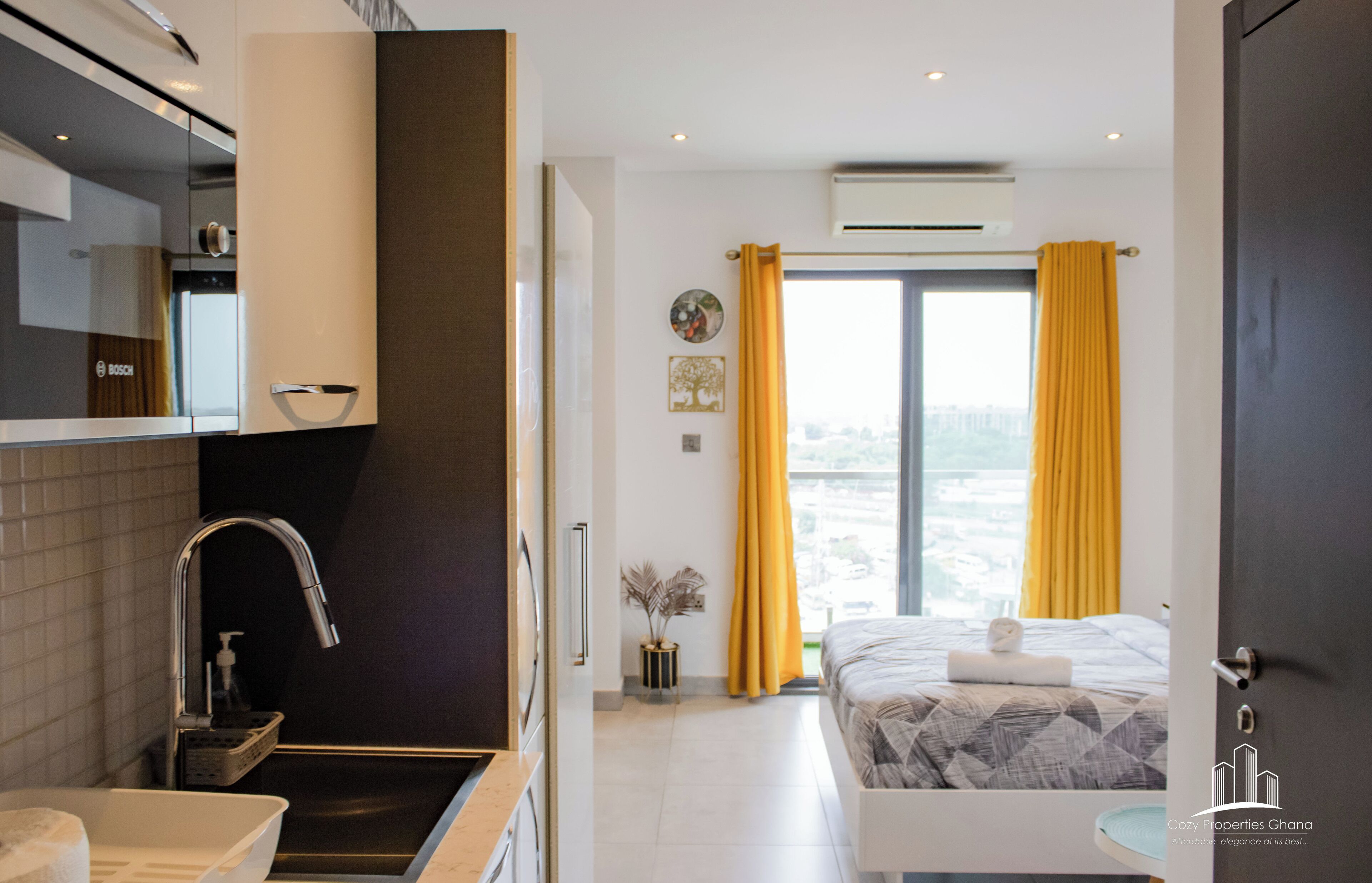 A modern hotel room with a large bed, a bathroom with a sink and mirror, and a view of the city through the window.