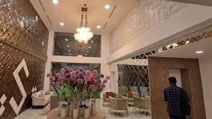 Un intérieur moderne avec un motif géométrique sur un mur, un arrangement floral central et un escalier menant à un niveau supérieur.