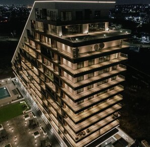 Een meerlaags hotel met een modern ontwerp, met balkons op elke verdieping en een terras op het dak.