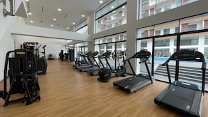 Une salle de sport équipée de tapis de course, de vélos elliptiques et de matériel de musculation.