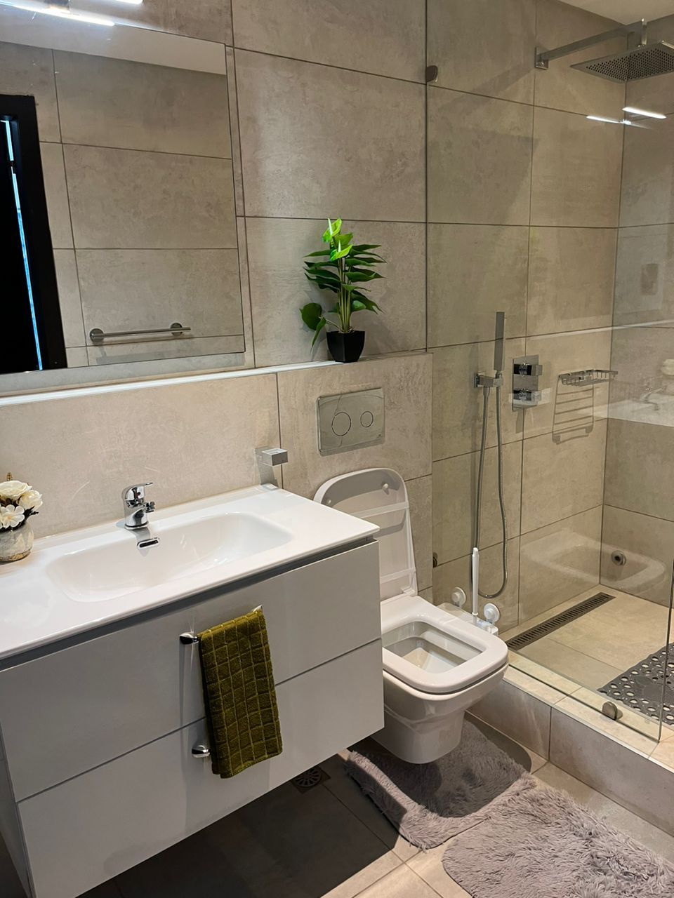Een moderne badkamer met douche, toilet en wastafel.