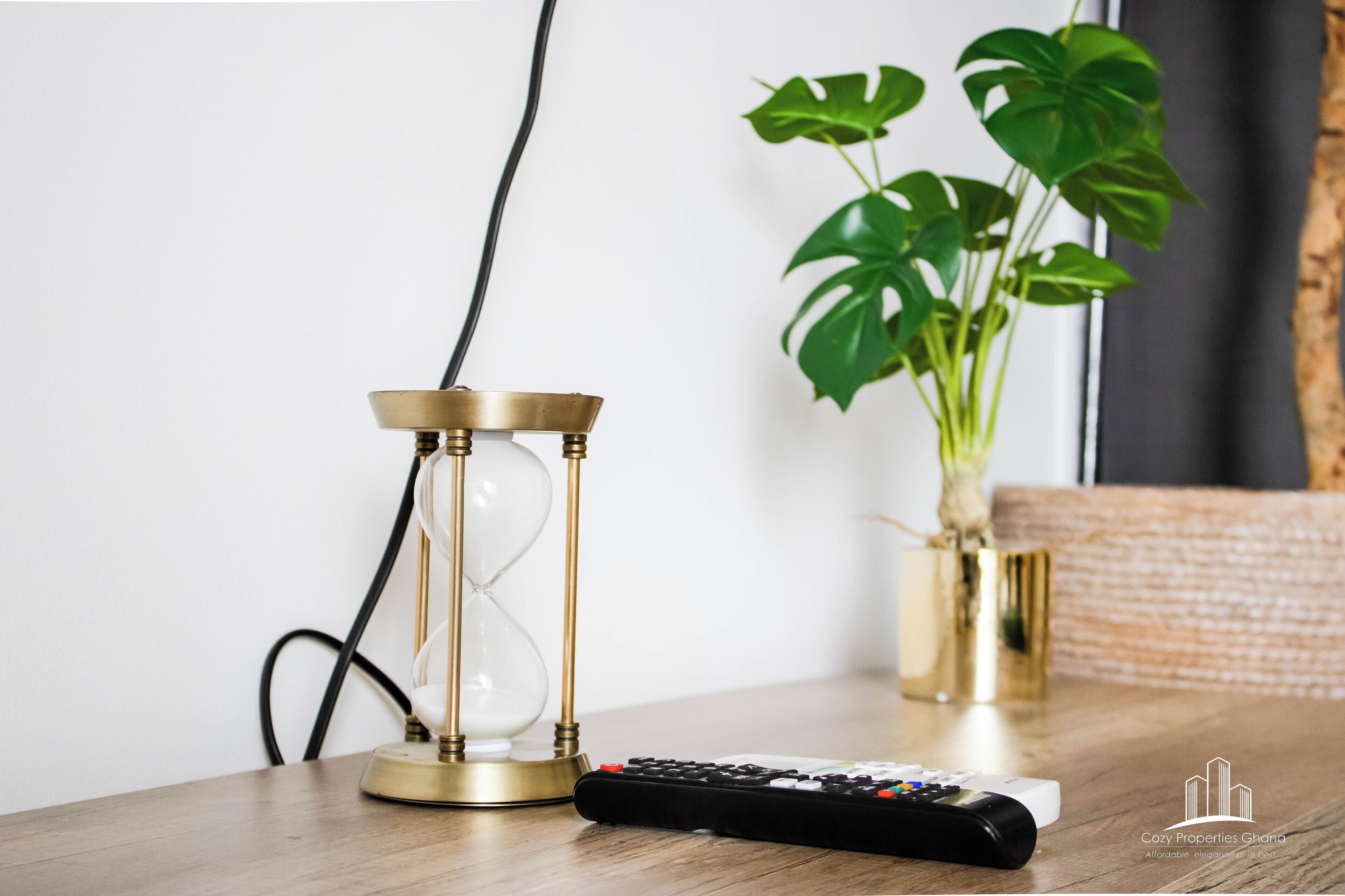 A wooden table with a remote control and an hourglass.