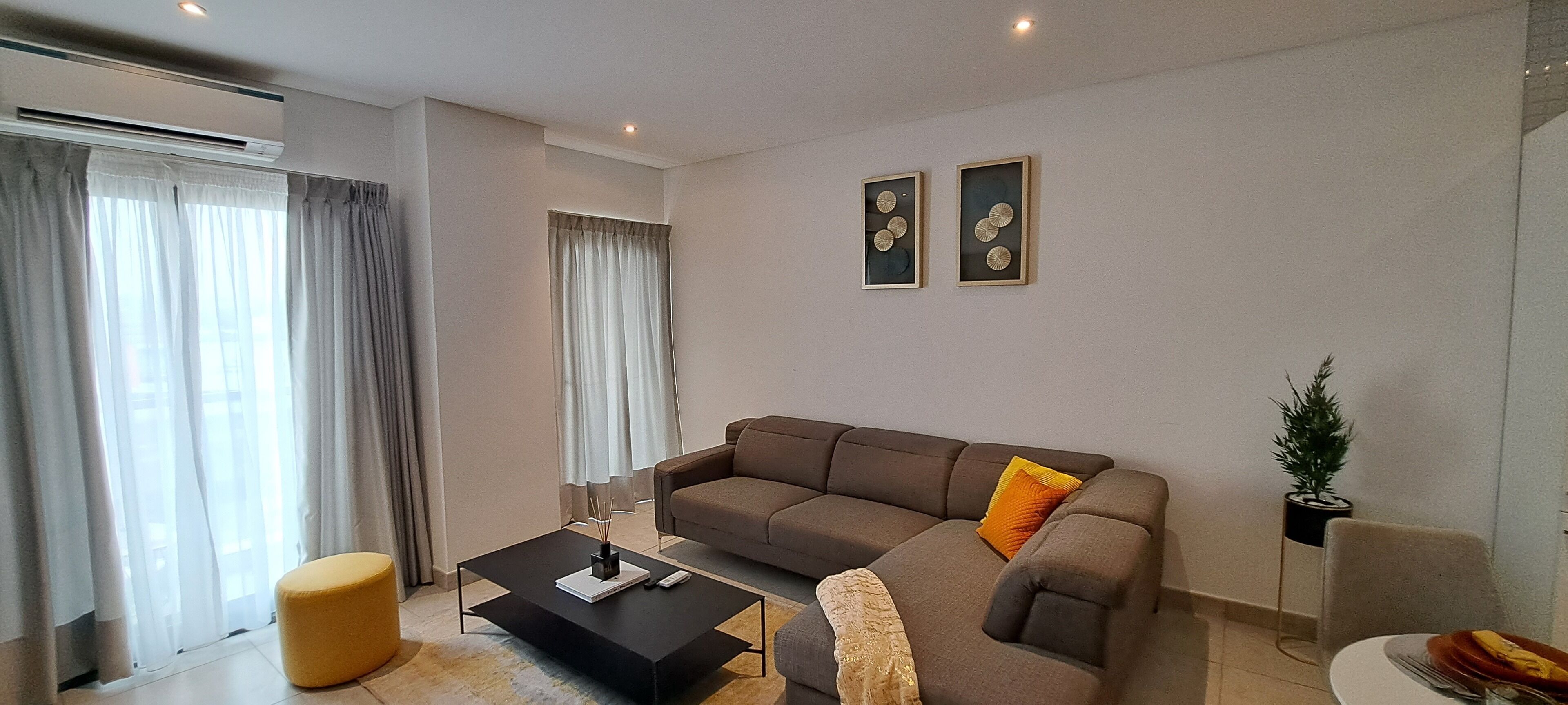 A modern living room with a sectional sofa, a coffee table, and a dining area.