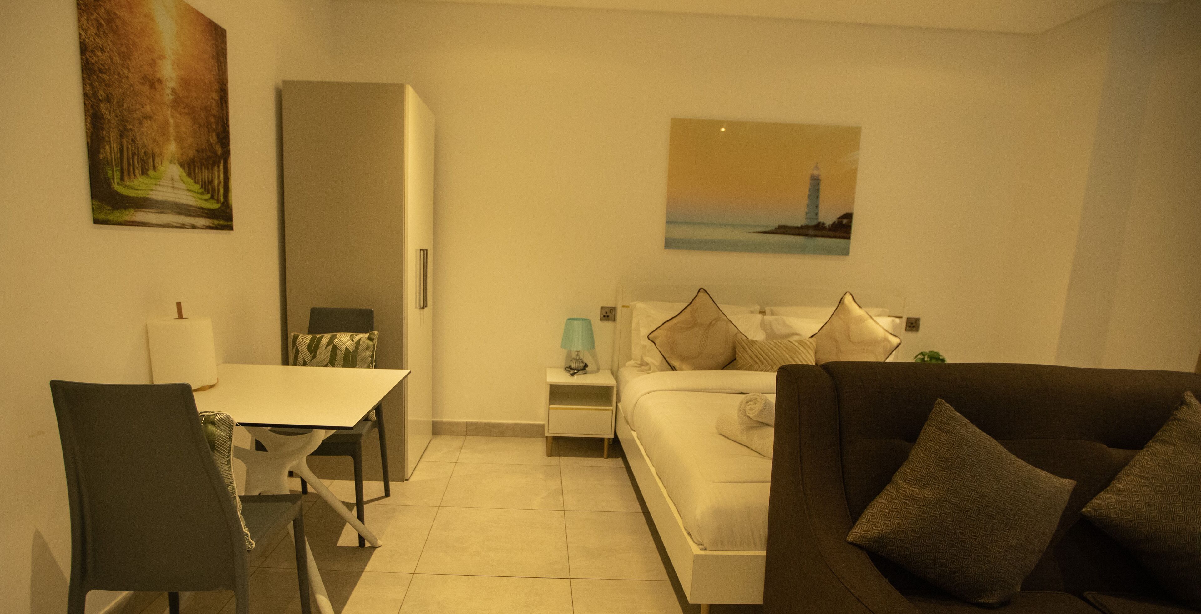 A hotel room with a bed, a sofa, a dining table, and a chair.