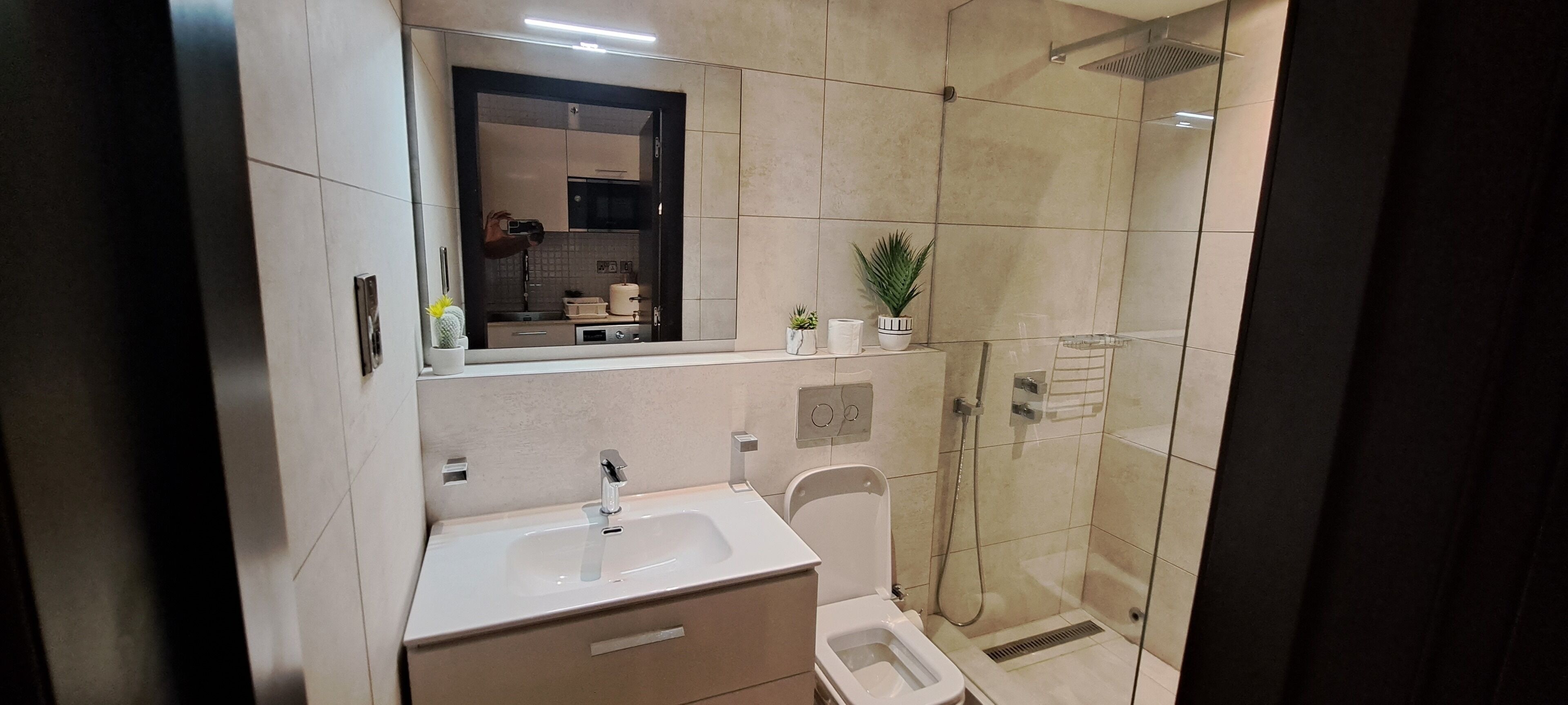 A modern bathroom with a sink, mirror, and shower.