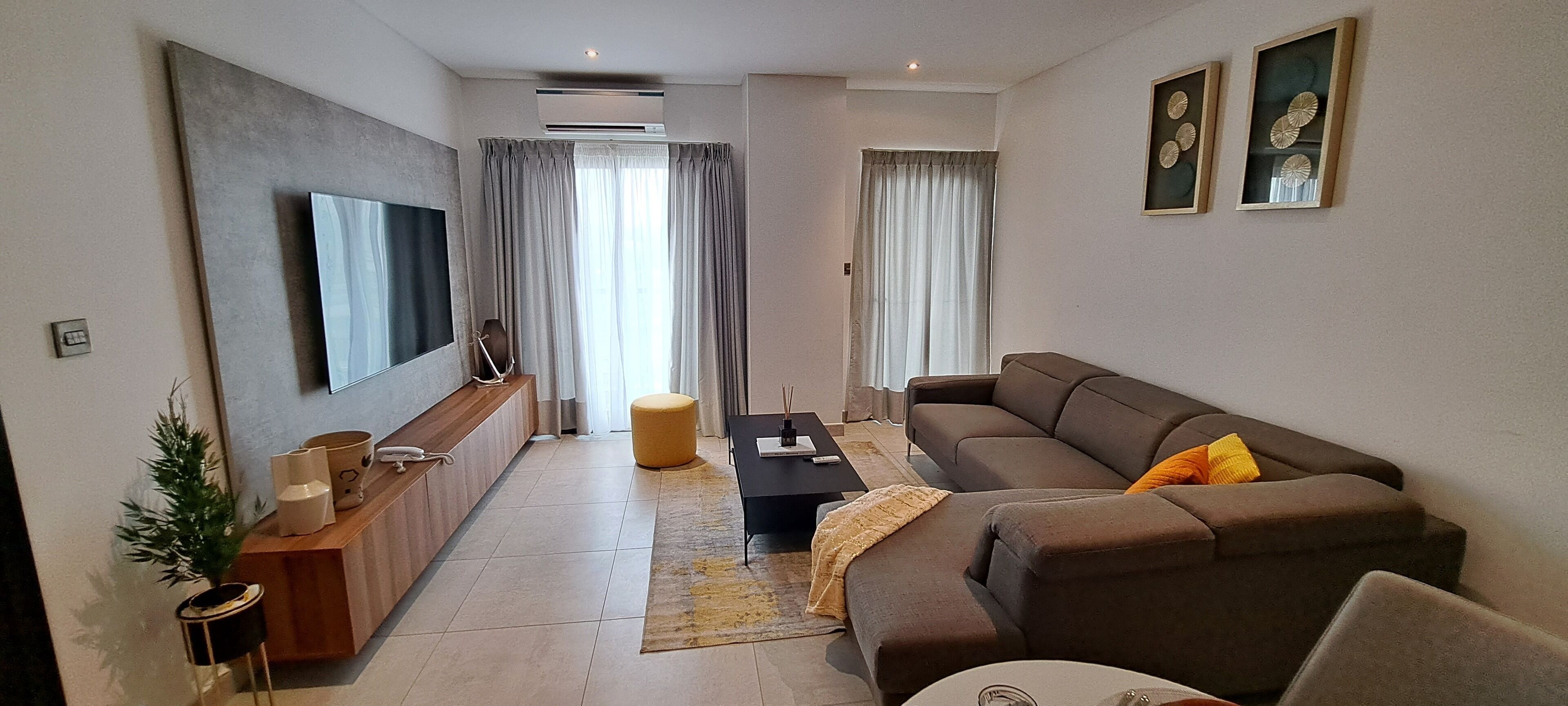 A modern living room with a sofa, a coffee table, a TV, and a small side table.
