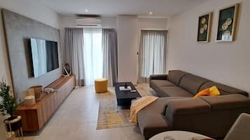 A modern living room with a sofa, a coffee table, a TV, and a small side table.
