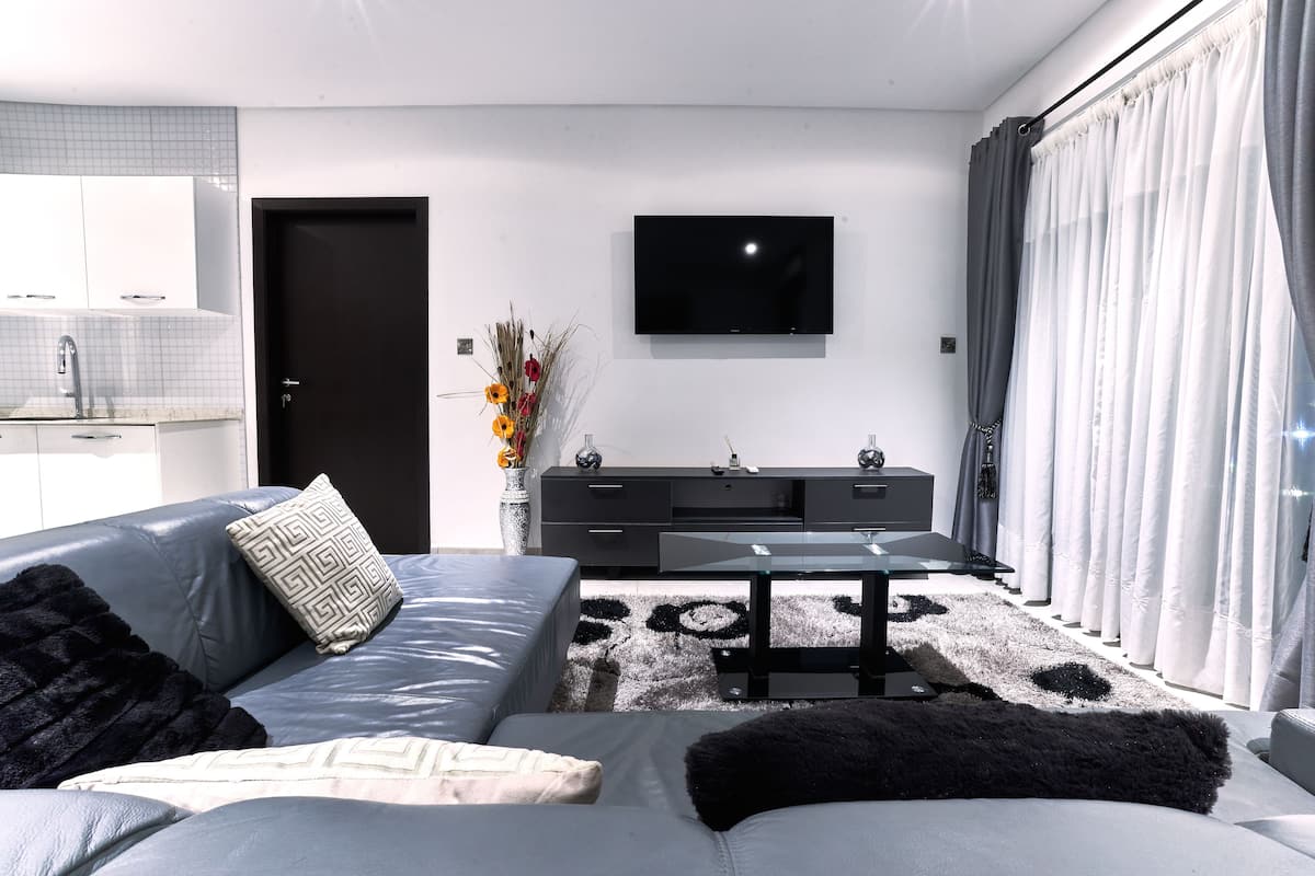 Una sala de estar moderna con un sofá, una mesa de centro y un televisor de pantalla plana montado en la pared.