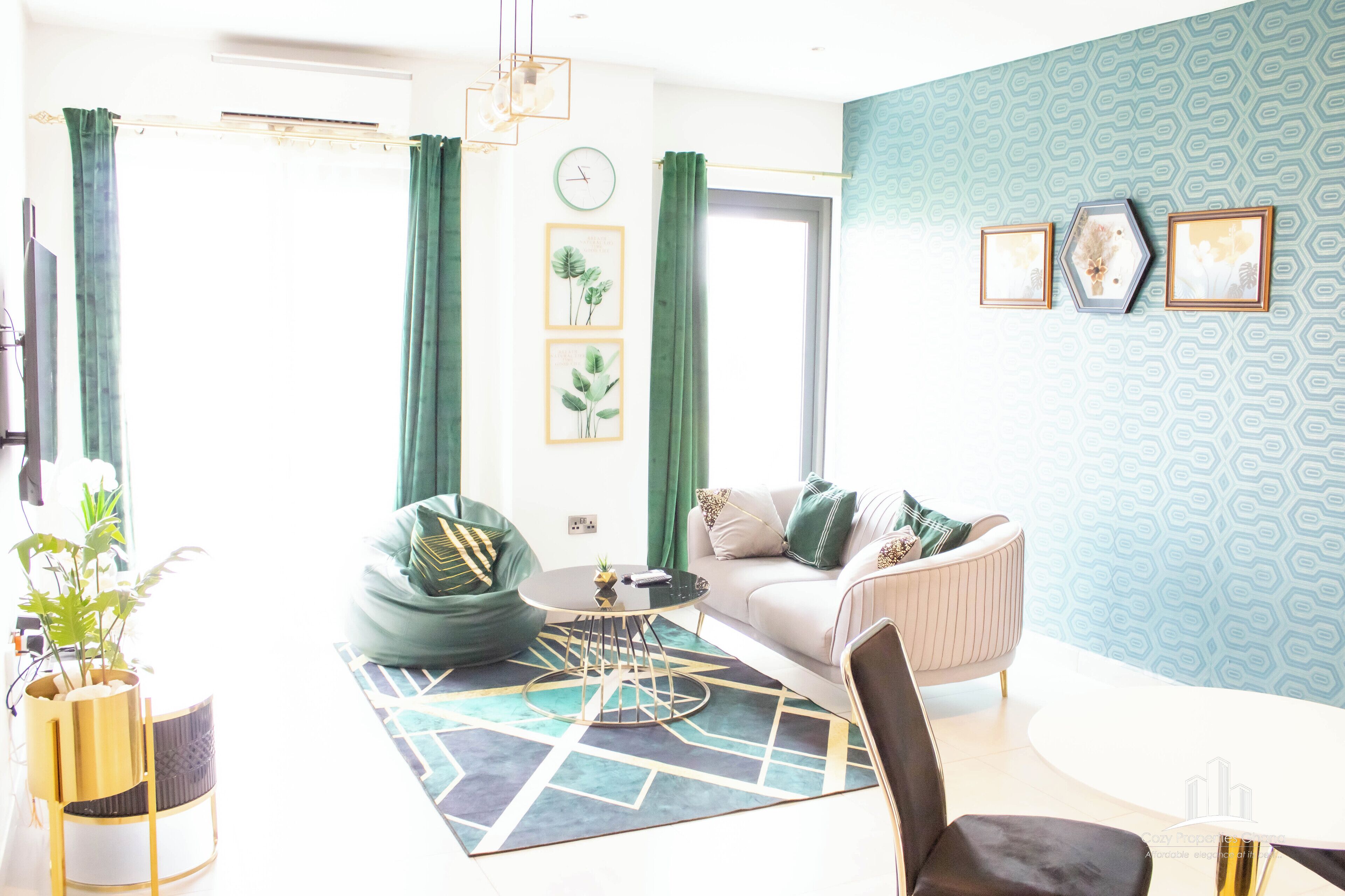 A modern living room with a sofa, green curtains, a coffee table, and a patterned rug.