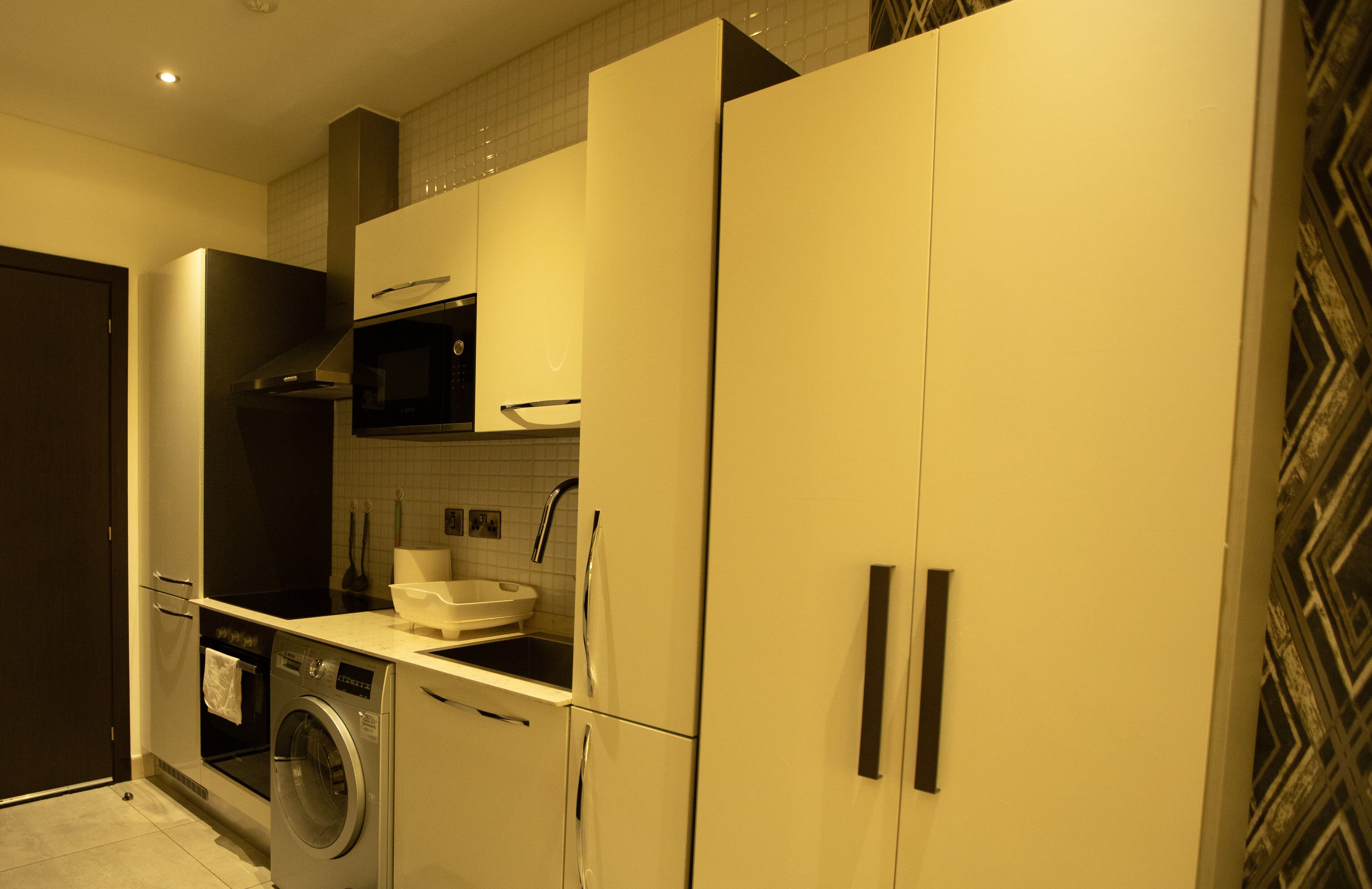 Une cuisine compacte équipée d’un lave-linge, d’un four à micro-ondes et d’un évier.