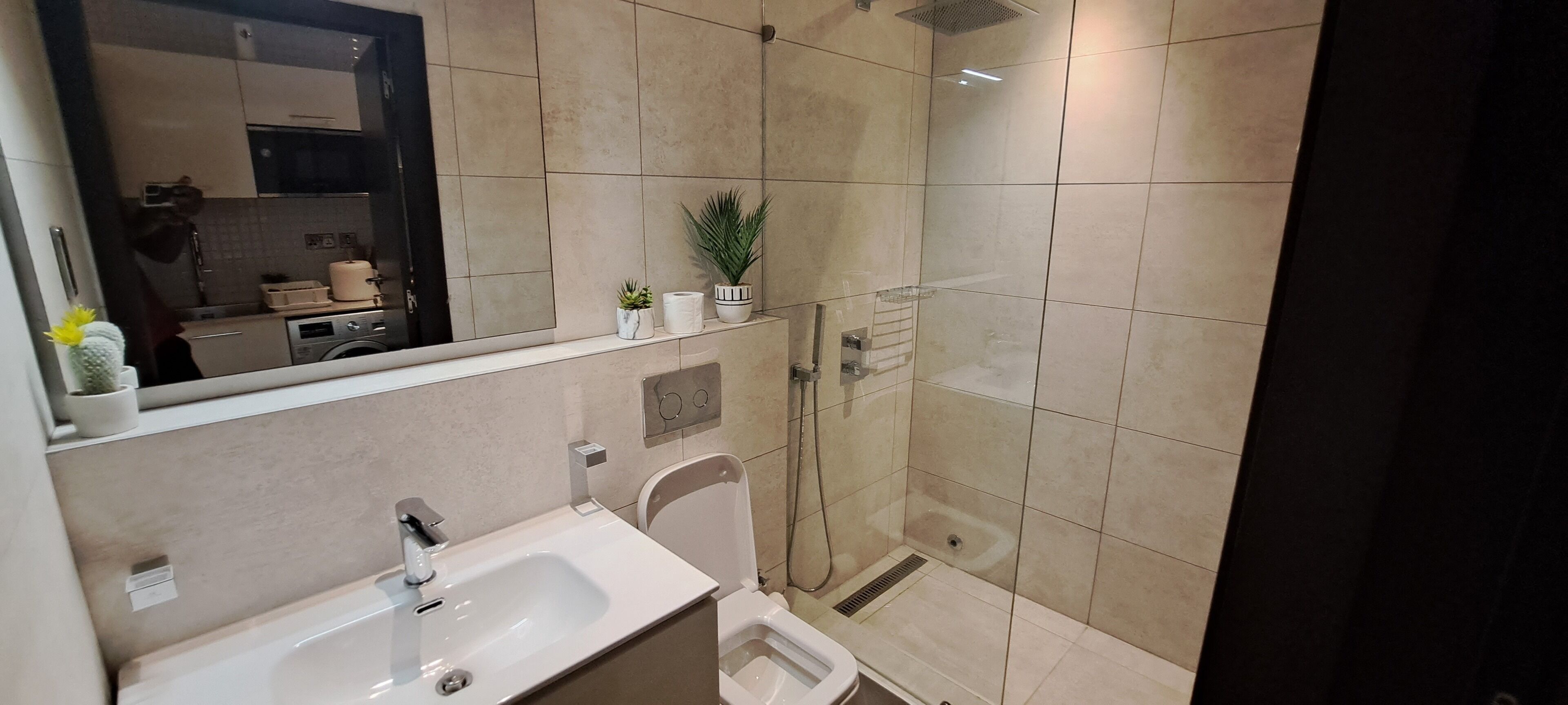A modern bathroom with a shower, sink, and toilet.