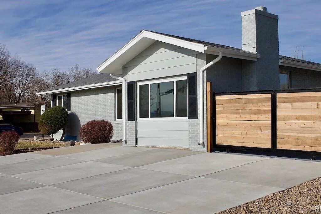 A modern two-story house with a garage, a covered driveway, and a wooden fence.