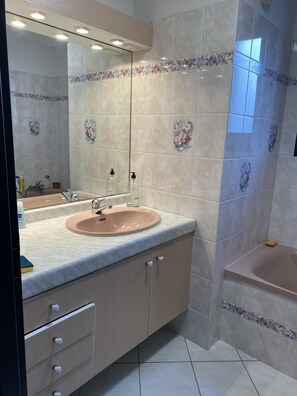 Une salle de bain avec un lavabo, un miroir et une baignoire.