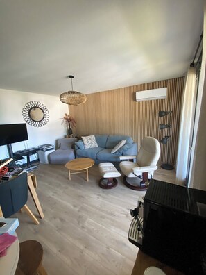 Un salon moderne comprenant un canapé, des fauteuils, une table basse, un téléviseur et une lampe.