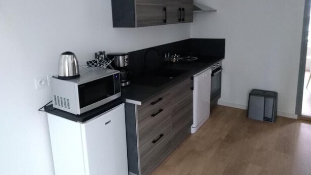 A compact kitchen with a microwave, kettle, and modern cabinetry.