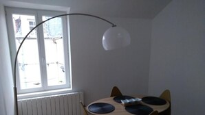 A dining area with a round table, four chairs, and a floor lamp.