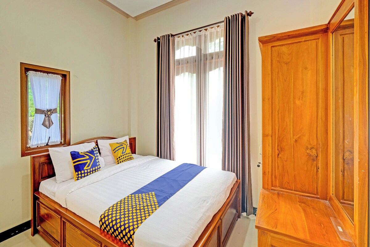 A bedroom with a wooden bed, a window with curtains, and a wooden wardrobe.