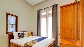 Un dormitorio con una cama de madera, un armario y una ventana con cortinas.