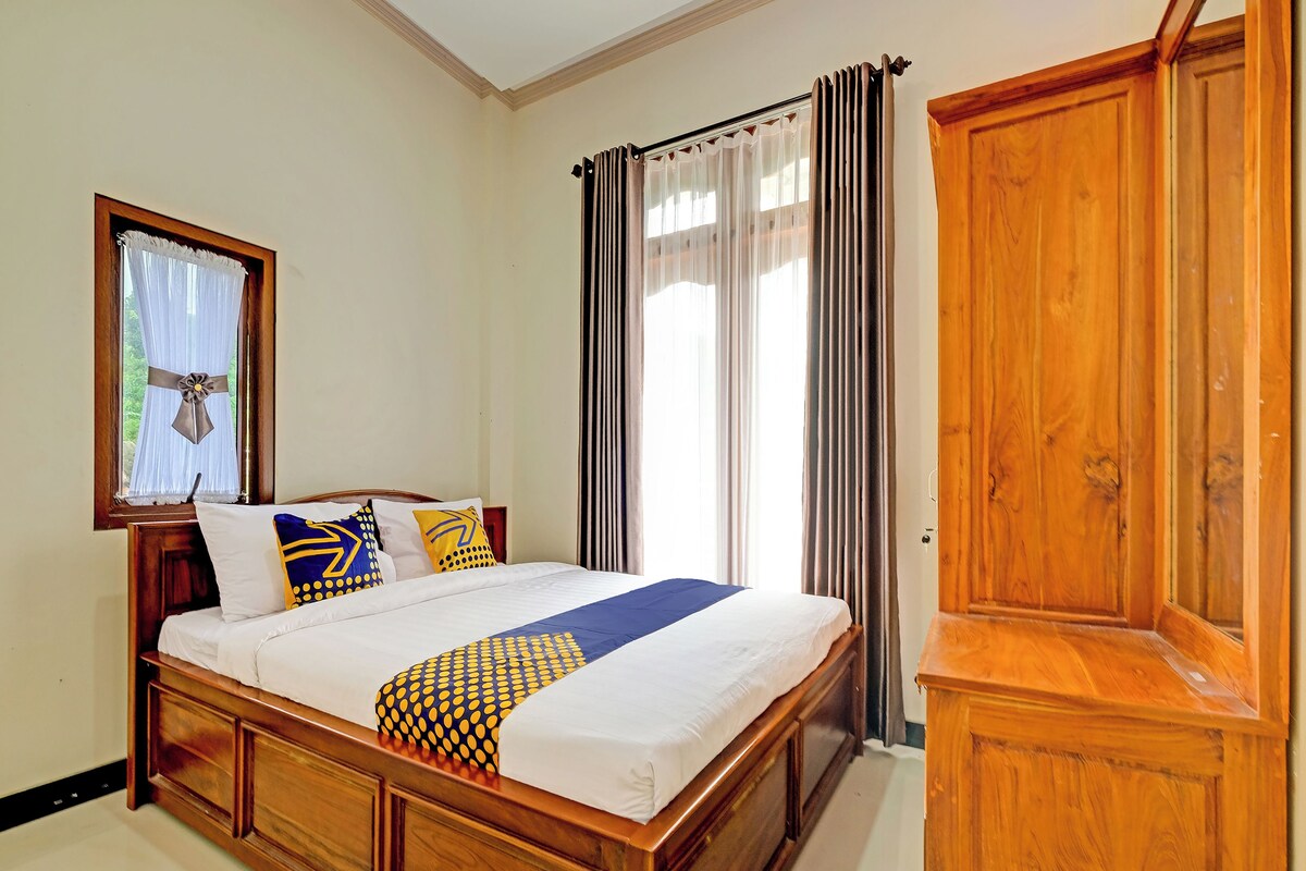 Ein Schlafzimmer mit einem hölzernen Bett, einem Kleiderschrank und einem Fenster mit Vorhängen.