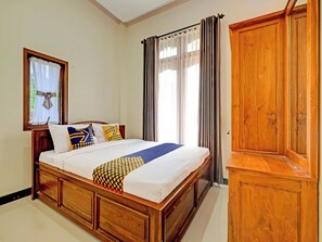 Ein Schlafzimmer mit einem hölzernen Bett, einem Kleiderschrank und einem Fenster mit Vorhängen.