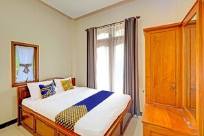 A bedroom with a wooden bed, a wardrobe, and a window with curtains. - Homes Desa Wisata Conto (Bulukerto)