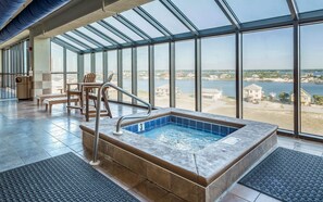 A glass-enclosed indoor pool with a view of a lake and buildings. - Phoenix IX by Brett Robinson Vacations (Orange Beach)
