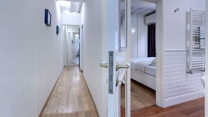 A hallway with a wooden floor leading to a bedroom with a bed and a white radiator. - Central Duomo Apartment With Fast Wifi (Florence)