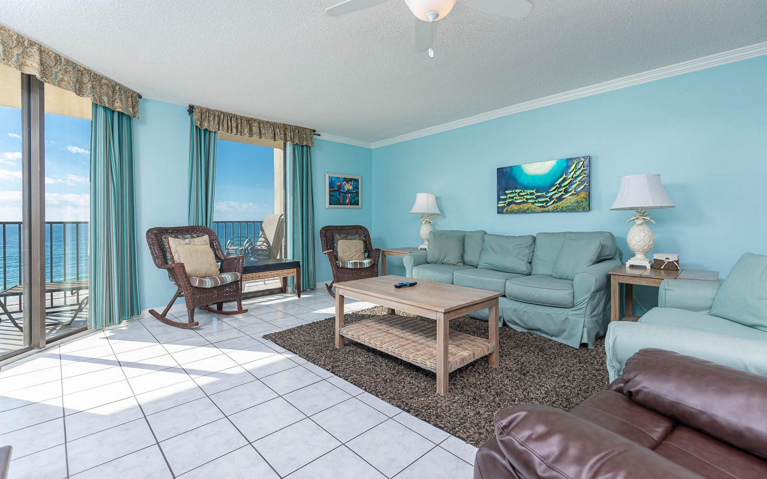 A living room with a view of the ocean, a sofa, a coffee table, and two chairs.