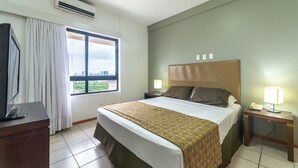 Een hotelkamer met een bed, twee nachtkastjes met lampen, een televisie en een raam met gordijnen.