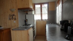 Une cuisine avec des murs en bois, une cuisinière, un réfrigérateur et une machine à café.