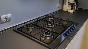 A kitchen with a gas stove, a coffee maker, and a black range hood. - Brand New 2-bed Apartment With Patio (Endine Gaiano)