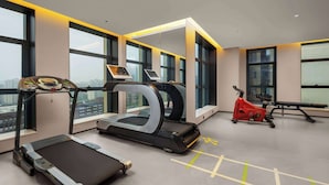 Une salle de sport moderne équipée de tapis de course, d’un vélo elliptique et d’un vélo d’appartement.