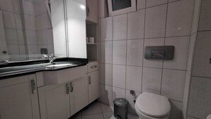 Ein modernes Badezimmer mit Waschbecken, Spiegel, Toilette und Mülleimer.