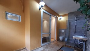 Ein Badezimmer mit Duschkabine, Waschbecken und Steinwand.