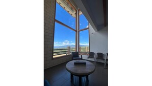 A room with large windows, a round table, and two chairs. - The village of San Juan (Villa de Leyva)