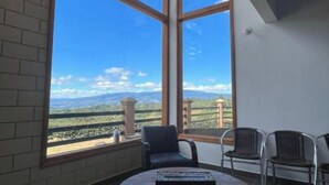 Una habitación con ventanas amplias, una mesa redonda y dos sillas.