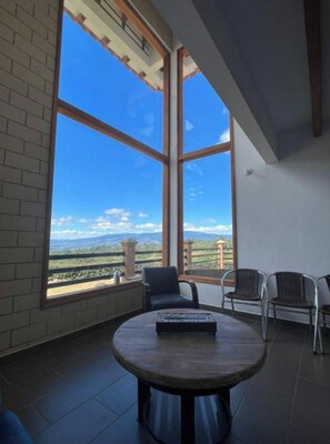 Una habitación con ventanas amplias, una mesa redonda y dos sillas.