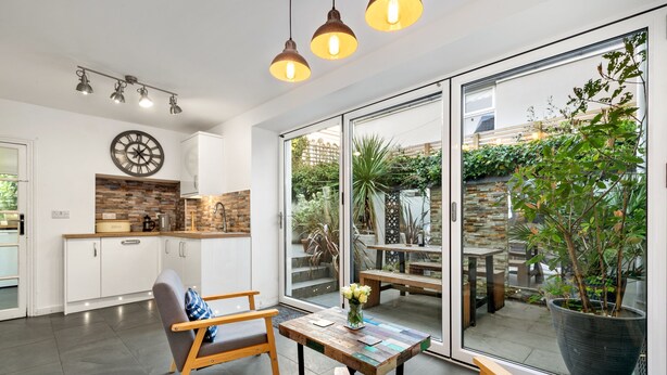 A modern kitchen with white cabinets, a wooden countertop, and a large window overlooking a garden.