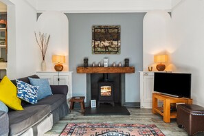 Un salon avec une cheminée, un canapé, un téléviseur et un tapis.