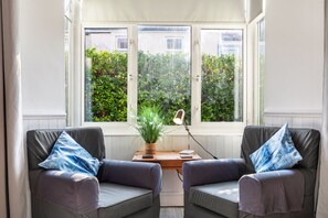 Una habitación con dos sillones grises, una mesa de madera y una planta en maceta.